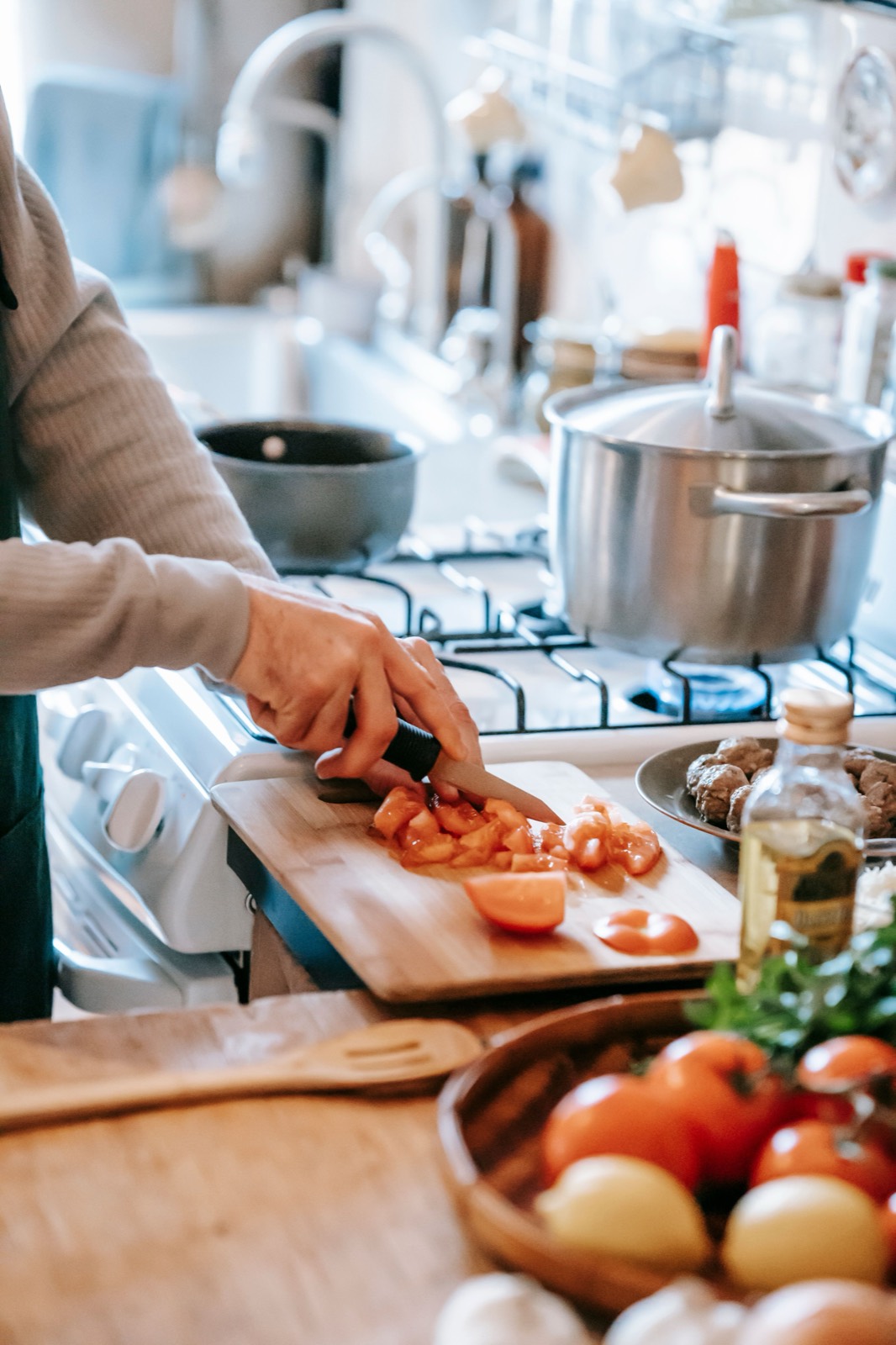 Une personne prépare un repas de légumes frais dans une cuisine chaleureuse, lumière naturelle.